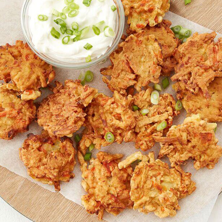 Recipe image of root vegetable fritters with Greek yoghurt dipping sauce, topped with green onions