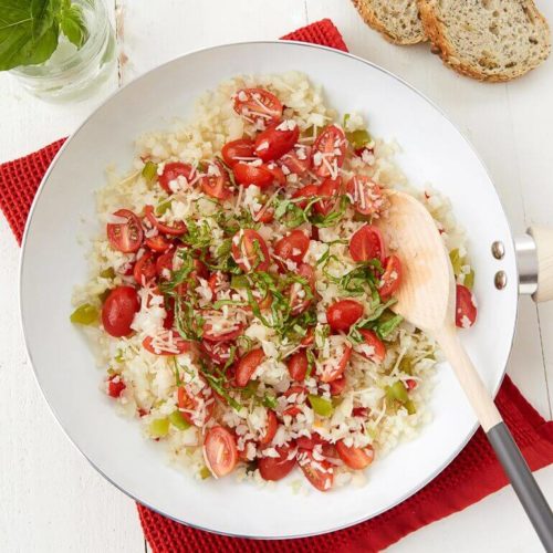 Recipe image of a bowl of organic tomato basil cauliflower rice topped with fresh basil